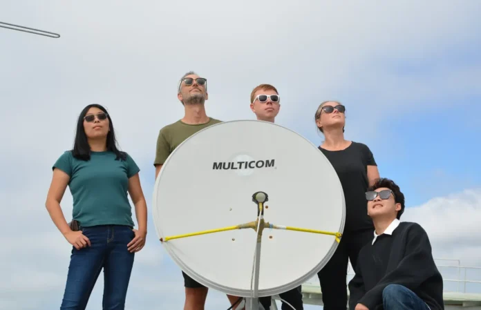 Para peneliti UCSD dan UMD berpose dengan sistem penerima satelit mereka di atap gedung universitas di San Diego