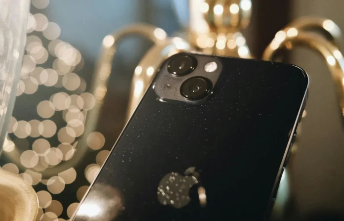 Closeup iPhone 13 dengan modul kamera menonjol di latar belakang blur dan pencahayaan dekoratif