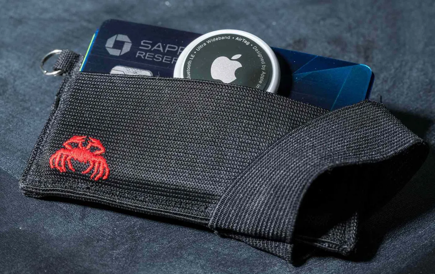 Dompet kartu kain dengan desain kepiting merah berisi kartu kredit Chase Sapphire Reserve dan Apple AirTag
