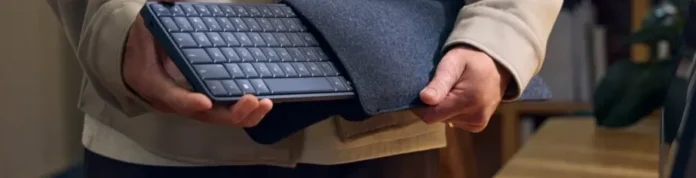 Keyboard HP EliteBoard G1a yang tipis diletakkan di atas meja kayu, merupakan PC Windows 11 lengkap.