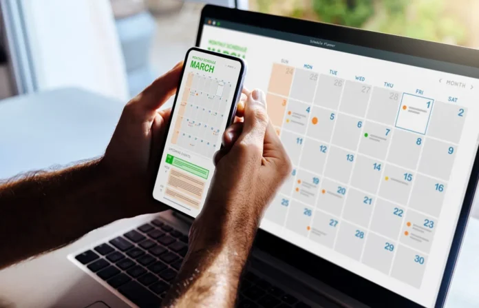 Seseorang melihat kalender yang ditampilkan di smartphone dan laptop secara bersamaan