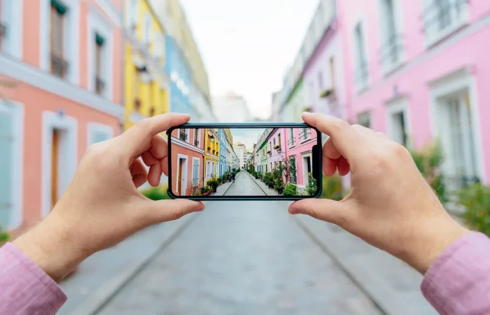 Ilustrasi seseorang memotret jalanan Rue Cremieux di Paris menggunakan smartphone, merepresentasikan pengujian aplikasi mobile.