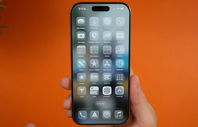 Tangan memegang iPhone menampilkan antarmuka mode gelap dengan latar belakang oranye